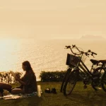Romantic sunset by the Lima coast – Peru Honeymoon Inspiration Couple reading together by the Lima coast during sunset, enjoying a romantic moment on their Peru honeymoon.
