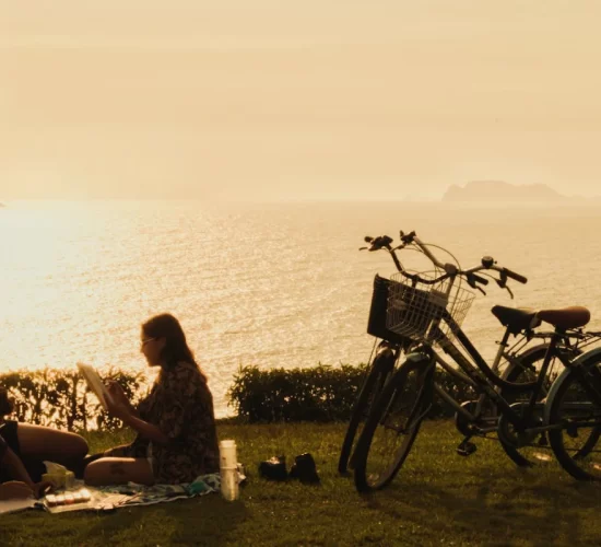 Couple reading together by the Lima coast during sunset, enjoying a romantic moment on their Peru honeymoon.